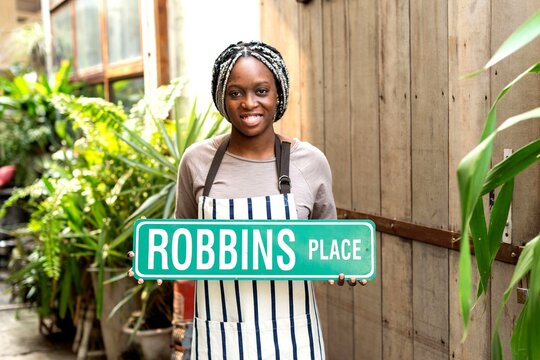 Smiling woman holding street sign.