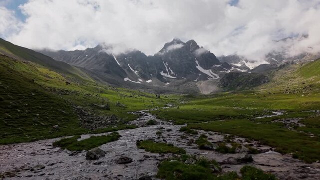 Aerial view of a winding alpine stream in a green valley