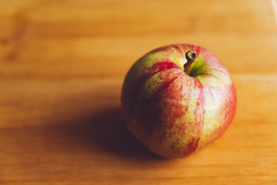 A striped apple on a wooden table.