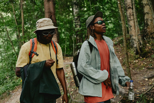 Diverse young adult African American friends hiking in forest, walking on trail with backpacks. Image suitable for outdoor recreation gear marketing and eco tourism campaigns