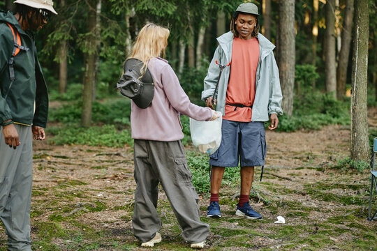 Diverse young adult friends collecting plastic waste in forest, promoting environmental conservation. Image suitable for eco friendly campaigns and community volunteering concepts