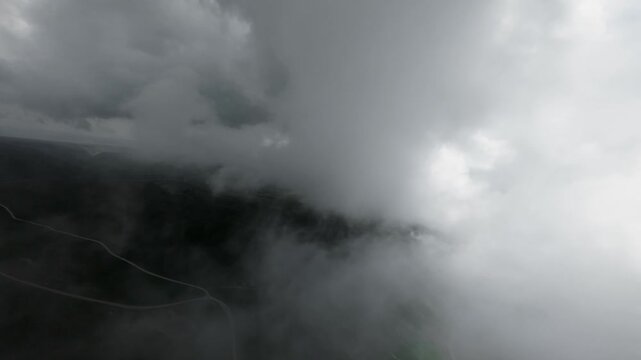 Aerial view ascending through dense clouds over mountainous landscape