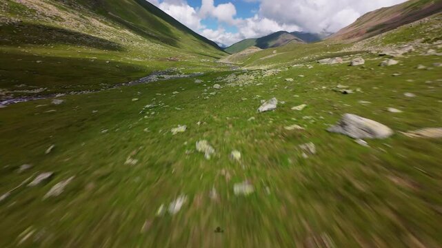 Rapid forward flight over mountain valley stream and rocks