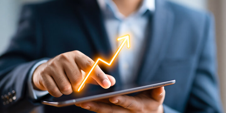 Close-up of a businessman's hand touching a tablet screen as a glowing orange growth arrow chart rises above it, representing rising profits, career momentum, and measurable success in a fast paced