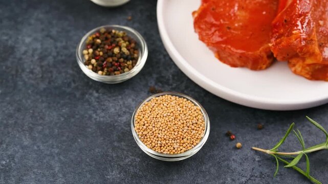 Marinated meat with peppercorns and mustard seeds on dark background