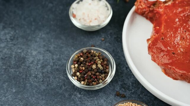 Raw meat preparation with spices and coarse salt on a dark background