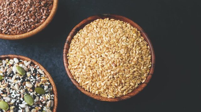 Three wooden bowls filled with assorted seeds against a dark background