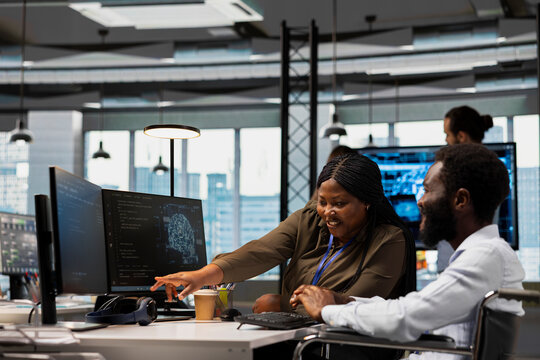 Programmer and colleague with paraplegia use artificial intelligence scripts to automate tasks and speed up feature implementation in an inclusive office.