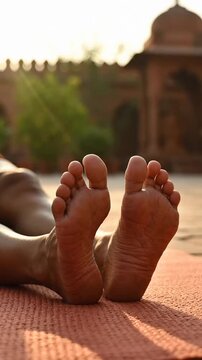 Close-up bare feet lying yoga mat outdoor meditation temple background vertical