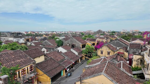 Panoramic high-angle view of red tiled roofs and yellow ancient buildings in Hoi An under a bright sky