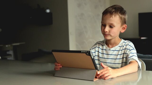 Little boy uses a tablet for home learning and speech therapy exercises, developing pronunciation, communication and language skills through digital lessons.