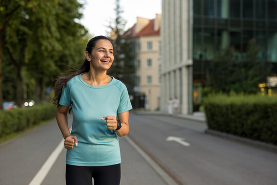 Smiling woman running outdoors on a city street, actively pursuing fitness goals while embracing a healthy lifestyle and urban exercise routine during the day