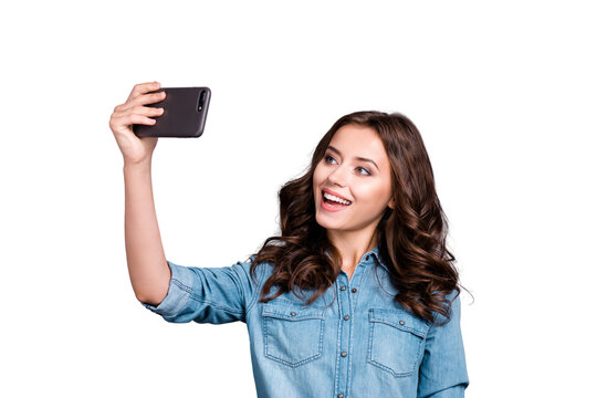 Stylish trendy confident flirty nice cute cheerful adorable lovely attractive magnificent brunette girl with wavy hair in casual denim shirt, taking selfie on cam, isolated over grey background