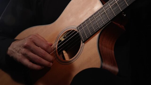 Close-up video of a guitarist playing, focusing on hands and vibrating strings against a black background, capturing musical performance, movement, rhythm, and detailed guitar textures.
