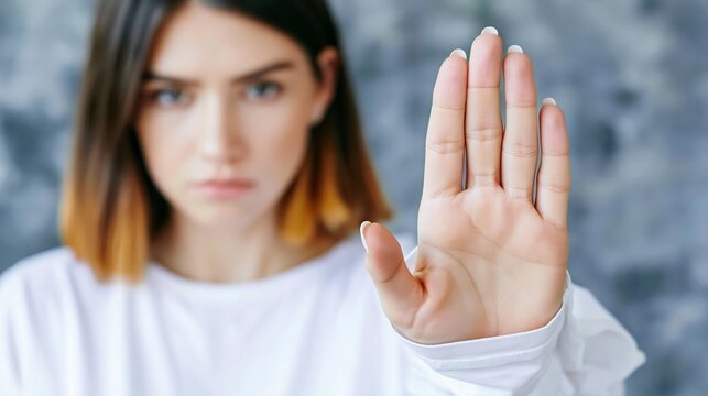 Young woman extending hand forward, making stop gesture, conveying rejection and boundaries