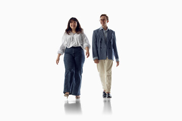 Fototapeta premium Fashionable couple walks forward in coordinated smart casual clothing. Concept of relationship style, modern wardrobe, confidence, togetherness and lifestyle fashion.