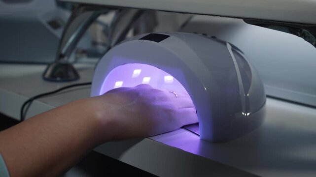 Fixing gel coating under ultraviolet lamp during manicure in beauty salon for durable and long lasting result