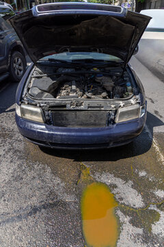 Dark Blue Sedan with Open Hood and Coolant Fluid Leak on Asphalt