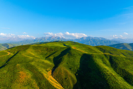 Aerial View of Green Rolling Hills and Snow-Capped Mountains