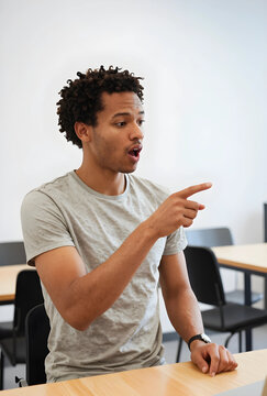 Surprise and discovery, young man pointing at something with shocked expression in classroom or office environment for communication and reaction concepts