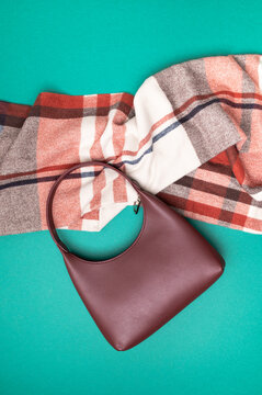 Burgundy handbag and checked scarf form autumn fashion layout on green background, showcasing coordinated accessories, seasonal style and product presentation for shopping and advertising.