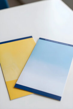 Corporate communication and brand identity, two blank brochures with yellow and blue gradient covers on a white desk for marketing and business design