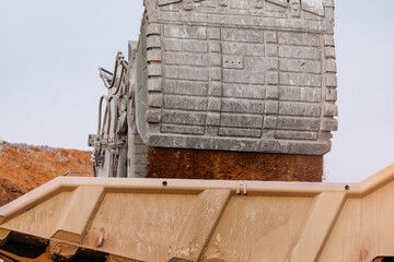 Closeup of excavator bucket dumping gold ore into dump truck for construction site background and industrial equipment © Parilov