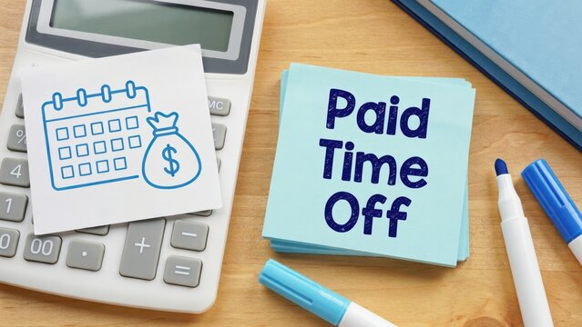 Paid Time Off text on a sticky note beside a calculator on a wooden desk. Concept for HR and employee benefits.