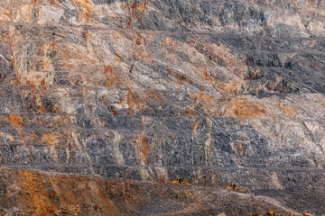 Massive open pit mine rock face background for industrial mining banner showing heavy haul trucks...