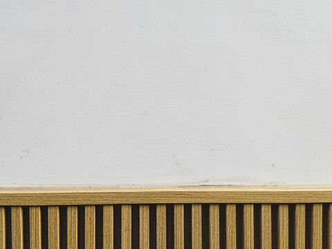 Wooden slatted panel against plain white wall