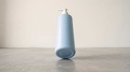 Light blue cosmetic pump bottle standing upright on a grey concrete surface © ChaohM
