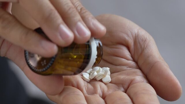 close up woman hand holding a medicine, with pours the pills out of medicine bottle. Stop drug use Taking Medication Caring for the health care medical concept.	