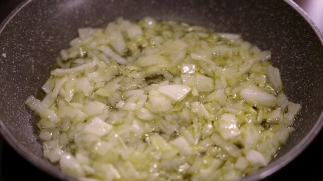 Chopped onion sauteing in olive oil in frying pan.