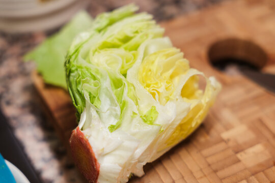 Fresh iceberg lettuce wedge on wooden cutting board ready to chop.