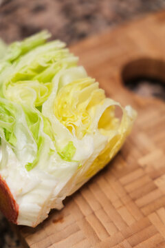 Fresh iceberg lettuce wedge on wooden cutting board ready to chop.