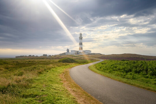 Route bitum&eacute;e sinueuse, sous les rayons du soleil, menant au phare du creac'h  &agrave; l'ouest de l'&icirc;le d'Ouessant en Bretagne, d&eacute;partement du Finistere