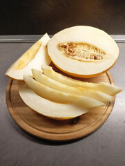Juicy cut melon on a wooden board.  A color photograph of a cut yellow melon on a wooden kitchen board. © Инна Федорова