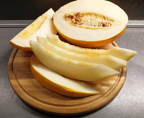 Juicy cut melon on a wooden board.  A color photograph of a cut yellow melon on a wooden kitchen board. © Инна Федорова