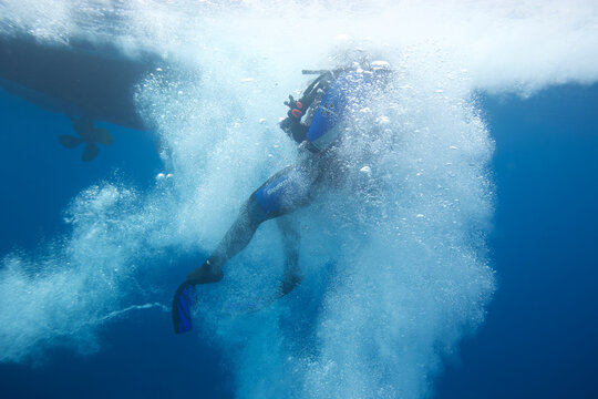 Scuba diver entering the water from a boat in the Pacific Ocean