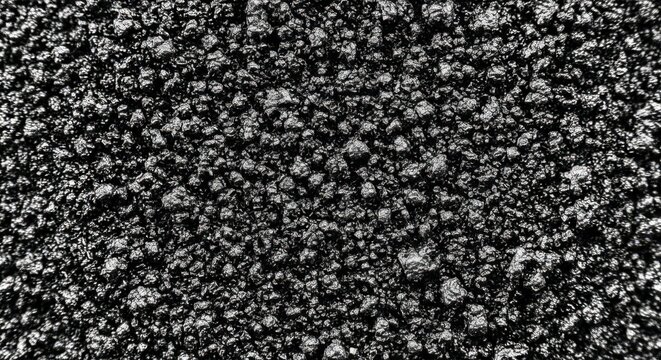 Close up macro view of rough dark charcoal texture with uneven bumpy surface, granular black with deep shadows and highlights, detailed mineral rock texture for background, or surface