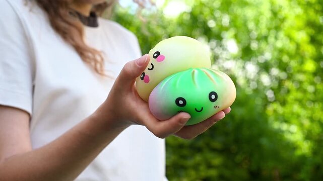 Girl holding two colorful dumpling-shaped squishy toys