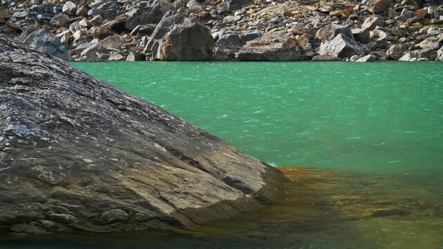 Low Altitude Aerial View of Rocky Ledge at Edge of Emerald Green Trollsj&ouml;n Lake in Abisko Sweden