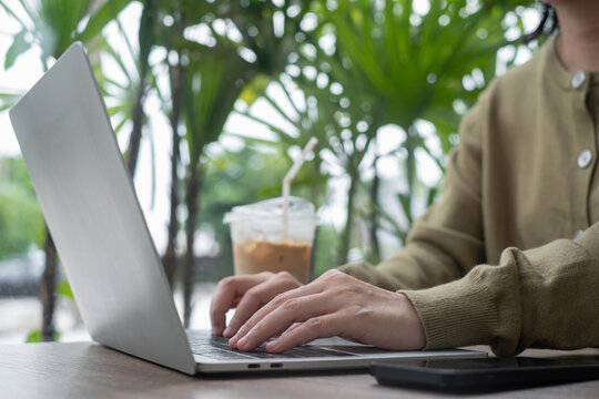 Remote work lifestyle with a professional using a laptop outdoors, enjoying coffee in a tropical setting, representing digital business, flexible work, productivity, and modern freelance careers.