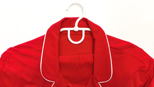 Red clothes with white trim on white hanger, garment item with classic collar, contrast trim and elegant vintage style.