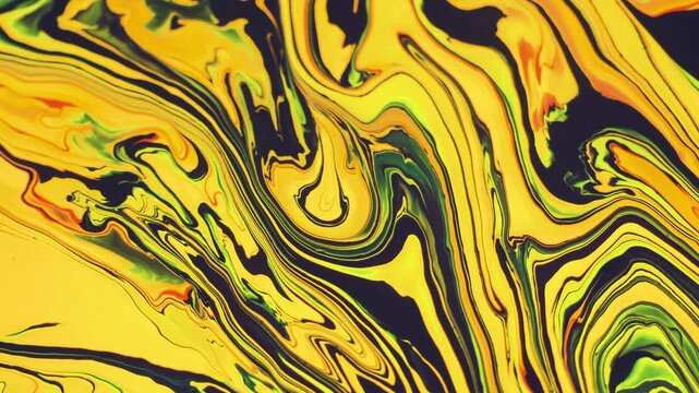 A slow-motion swirl of bright yellow, green, and black acrylic paint blending to form a hypnotic marbling pattern.