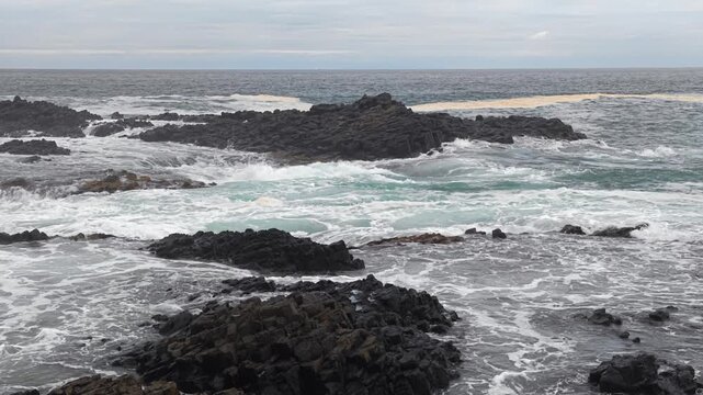 岩に波が打ち寄せる荒れた海の風景。