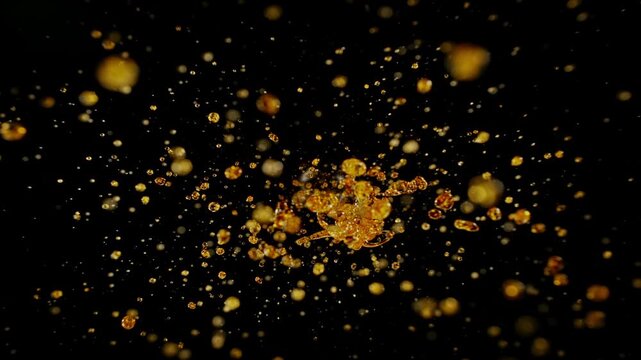 Super slow motion video of a whiskey or cider splash isolated against a black background, capturing flying droplets, liquid motion, reflections, and dynamic fluid shapes in high detail.