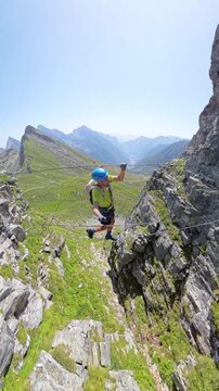 Climber crossing a suspended cable bridge on Via Ferrata di Cimalegna. Alagna, Italy