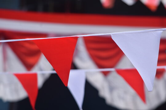 Close-up of red and white triangular bunting flags hanging for celebration. Ideal for Indonesian Independence Day, festival, carnival, national event, and party decoration backgrounds.