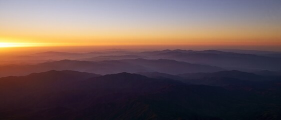 Obraz premium The Sunrise Over Misty Mountain Ridge at Dawn with Golden Horizon